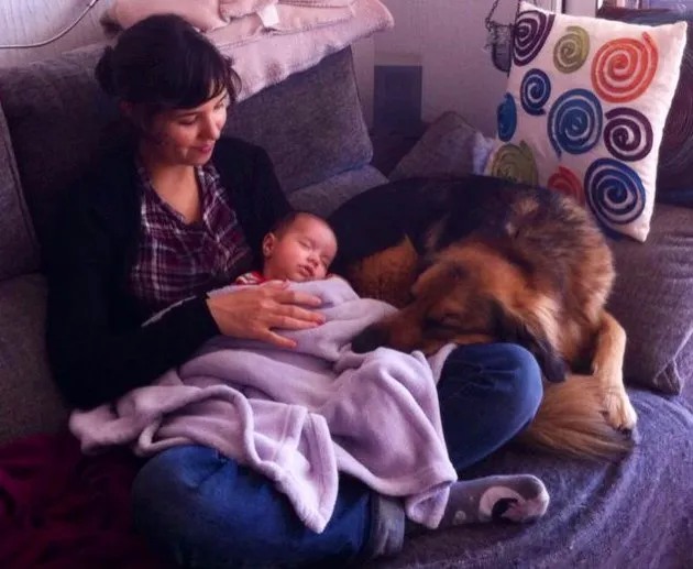 Alba en el sofá con su bebé dormido en brazos y su perro tumbado tranquilo a su lado